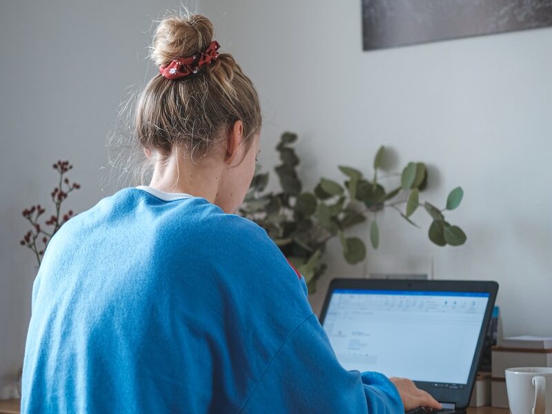 woman in blue sweater sitting in front of laptop computer